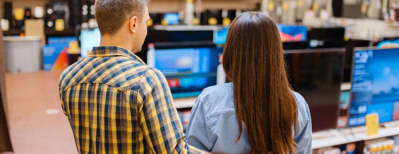Family couple choosing TV in electronics store. Man and woman buying home electrical appliances in market